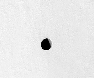 Later image of hole on the side of Arsia Mons showing the side of the pit illuminated. CREDIT: NASA/JPL/University of Arizona